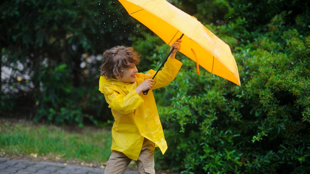 Ein Kind in Regenkleidung kämpft bei Wind und Regen mit einem geöffneten Regenschirm | Bild: colourbox.com
