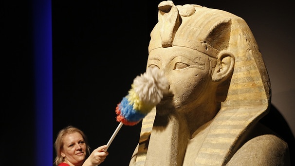 Eine Mitarbeiterin des Museums staubt den Kopf einer Sphinx der Königin Hatschepsut ab. Ein Exponat der Rosenheimer Pharao-Ausstellung | Bild: picture-alliance/dpa