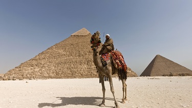 Ein Mann auf einem Kamel vor der berühmten Chephren-Pyramide von Gizeh | Bild: picture-alliance/dpa