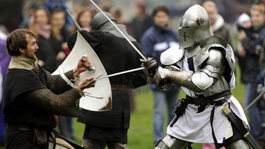 Mit Schwertern tragen Ritter des Templer-Ordens und der Welfschen Ministerialien einen Schaukampf im Rahmen von Ritterspielen in Hannover gegeneinander aus.  | Bild: picture-alliance/dpa