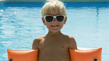 Junge mit Sonnenbrille und Schwimmflügeln | Bild: Getty Images