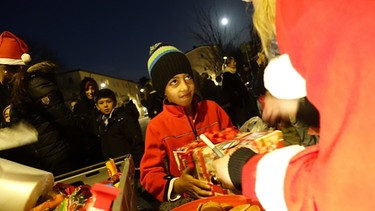 Flüchtlingskinder werden im Dezember 2015 in Schweden von einem Weihnachtsmann beschenkt.  | Bild: picture-alliance/dpa
