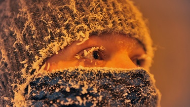 Ein junges Mädchen, eingemummt mit Schal und Mütze und mit kleinen Eiszapfen an ihren Wimpern. | Bild: picture alliance / dpa | Kozhevnikov Denis
