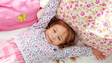 Ein Mädchen wacht in ihrem Bett auf und streckt sich. | Bild: colourbox.com