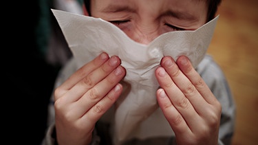 Ein Kind niest in ein Taschentuch. | Bild: dpa-Bildfunk/Nicolas Armer