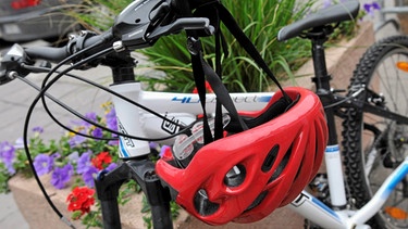 Ein Fahrradhelm hängt an einem Moutainbikelenker. | Bild: colourbox.com