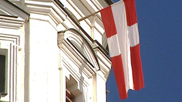 Der "Zachäus", eine rotweiße Fahne hängt am Raistinger Kirchturm | Bild: BR