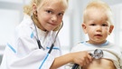 Ein kleines Mädchen untersucht wie eine Ärztin mit einem Stethoskop einen kleinen Jungen. | Bild: colourbox.com