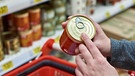 Beim Einkauf: Eine Kundin legt eine Konservendose in ihren Einkaufswagen. | Bild: colourbox.com