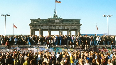 Menschenmenge am 10. November 1989, dem Tag des Mauerfalls, vor und auf der Berliner Mauer vor dem Brandenburger Tor.  | Bild: picture-alliance/dpa