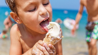 Ein Junge schleckt genüsslich ein Eis am Strand. | Bild: colourbox.com