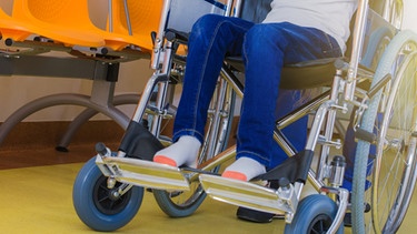 Die Beine eines Kindes, das im Rollstuhl sitzt. | Bild: colourbox.com