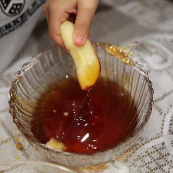 Am jüdischen Neujahrsfest Rosch Haschana ist es Brauch Apfelschnitze in Honig zu tauchen.  | Bild: picture alliance / AP Images | Will Vragovic