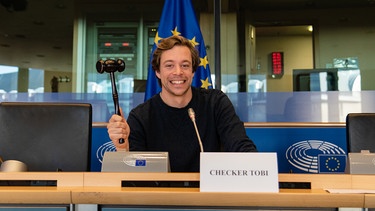Der Europa-Check | Checker Tobi in einem Sitzungssaal in Brüssel. | Bild: BR / megazerz gmbh; Hans-Florian Hopfner