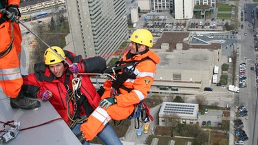 Vorfahrt für die Feuerwehr! / Willi Weitzel (links) mit dem Höhenretter Berni von der Berufsfeuerwehr München am Hypobankgebäude in München. | Bild: BR/megaherz
