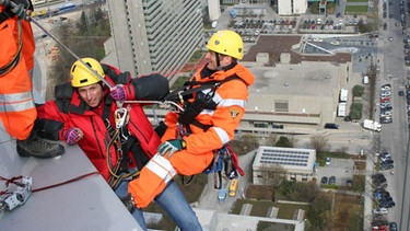 Vorfahrt für die Feuerwehr! / Willi Weitzel (links) mit dem Höhenretter Berni von der Berufsfeuerwehr München am Hypobankgebäude in München. | Bild: BR/megaherz