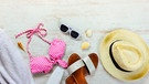 Bikini, Sonnenbrille, Sonnenhut und diverse anderes Utensilien, die man in den Ferien oder im Sommer braucht. | Bild: stock.adobe.com/dil_ko