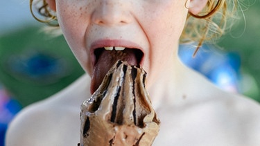 Ein Junge schleckt ein Schokoladeneis im Schwimmbad. | Bild: BR/Julia Müller
