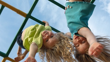 Kinder hängen auf dem Spielplatz kopfüber vom Klettergerüst. | Bild: colourbox.com