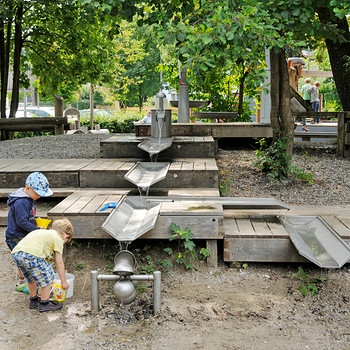 Auf dem Spielplatz in Frasdorf: Wasserrinnensysteme und ein kleines Wasserrad, an dem zwei Jungen spielen. | Bild: Richter Spielgeräte