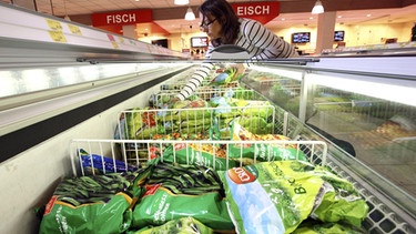 Eine Frau kauft im Supermarkt aus einer Tiefkühltheke tiefgefrorenes Gemüse ein. | Bild: picture alliance/imageBROKER