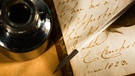 Schreiben mit altertümlicher Feder und Tintenfass. | Bild: colourbox.com