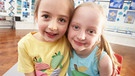 Zwei Mädchen, die sich umarmen, in einem Klassenzimmer. | Bild: colourbox.com
