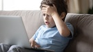 Ein Junge sitzt vor einem Laptop und fasst sich erschrocken an die Stirn. | Bild: colourbox.com