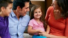 Ein Mann und eine Frau sitzen mit ihren Kindern auf einem Sofa und sprechen miteinander. | Bild: colourbox.com
