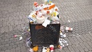 Überquellender Mülleimer in der Fußgängerzone | Bild: picture-alliance/dpa