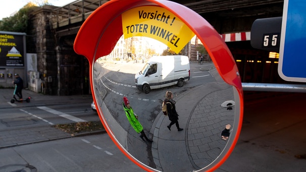 Ein Trixi-Spiegel mit dem Hinweis "Vorsicht! Toter Winkel" hängt an einer Straßenkreuzung in München. Der Spiegel soll den toten Winkel beim Abbiegen von großen Fahrzeugen reduzieren und damit die Sicht auf Fußgänger und Radfahrer verbessern.  | Bild: picture-alliance/dpa | Sven Hoppe
