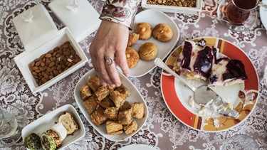Asse trinkt mit einer Freundin Tee und isst besondere Süßigkeiten zum Zuckerfest. Für Millionen Muslime endet mit dem Feiertag Eid al-Fitr der heilige Fastenmonat Ramadan.  | Bild: dpa-Bildfunk/Eman Helal