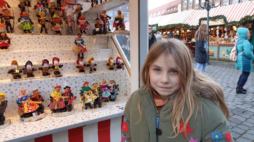 Die neunjährige Kinderreporterin Nina-Fee beim Stand mit den Zwetschgenmännla auf dem Nürnberger Christkindlesmarkt. | Bild: BR | Eleonore Birkenstock