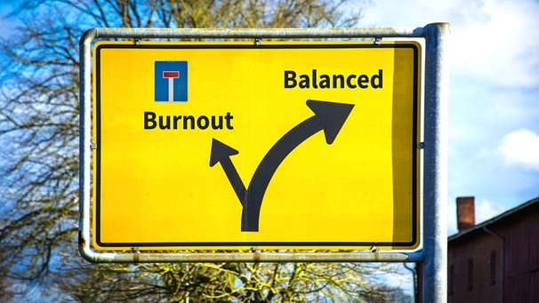 Ein gelbes Straßenschild, darauf eine Weggabelung mit den Richtungen Burnout und Balance | Bild: picture alliance / Zoonar / Thomas Reimer