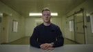 Maximilian Schmidt sitzt mit ernstem Blick in einem Gefängnisraum in einer Szene aus dem Dokufilm "Shiny_Flakes: The Teenage Drug Lord" von Netflix | Bild: Netflix