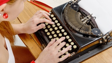 Nahaufnahme der Hände einer jungen Frau mit einer alten Schreibmaschine | Bild: picture alliance / PantherMedia | Renaud Philippe