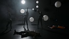Drei Frauen in dunklen hautengen Anzügen, auf dem Boden liegen zwei Männer. | Bild: Theater Bambereg