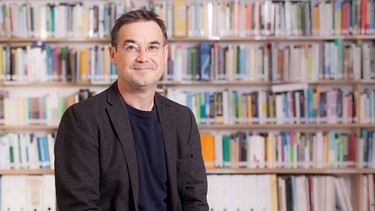 Porträt des Verlegers Jakob Radloff vor einer Bücherwand | Bild: Johannes Haslinger