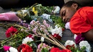27.06.2022, Spanien, Sevilla: Männer liegen bedeckt mit Blumen auf dem Boden während einer Kundgebung nach dem Tod vieler Migranten bei dem Ansturm auf die spanische Exklave Melilla. | Bild: dpa-Bildfunk/Angel Garcia