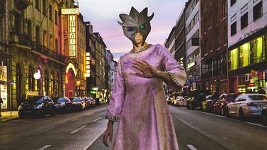 Bild zu "Introduction to the Future Self": Musiker und Texter Flo Kreier im pinken Kleid mit einer Alien-Echsen-Maske über dem Gesicht in einer Straße Münchens | Bild: Milena Wojhan