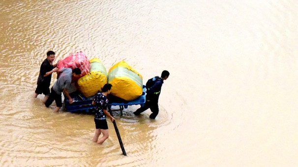Zhengzhou: Anwohner tragen nach der schweren Überschwemmung in zentralchinesischen Provinz Henan ihre Habseligkeiten über eine überflutete Straße | Bild: dpa-Bildfunk/Zhu Xiang