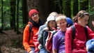 Jugendliche sitzen auf einem Baumstamm im Bayerischen Wald | Bild: BR/Bildungsprojekte