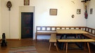 Der "Herrgottswinkel" einer Bauernstube mit Tisch und mauerfernen Bänken | Bild: Zweckverband Dachauer Galerien und Museen
