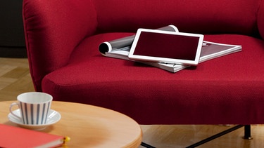 Tablet-PC und Zeitschrift liegen auf rotem Sessel. | Bild: MEV_Aktuelles Fotoarchiv_121 | Mira Hanak