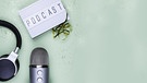 Ein Aufnahmemikrophon, ein Kopfhörer und ein Schild auf dem "Podcast" steht. | Bild: stock.adobe.com/faveteart
