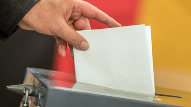Ein Wahlzettel wird in die Wahlurne geworfen. | Bild: dpa-Bildfunk/Michael Kappeler