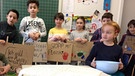 Klassen mit Demo-Schildern gegen Plastik und zwei Kinder an einem Tisch sitzend mit Plastikschale. | Bild: BR / Silke Wolfrum