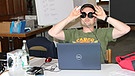 Ein Teilnehmer sitzt vor einem Laptop und biegt die Kopfhörermuscheln zu Brillengläsern. | Bild: BR
