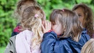 Hände am BR Mikrofon, Kinder flüstern sich gegenseitig etwas zu | Bild: BR, colourbox.com