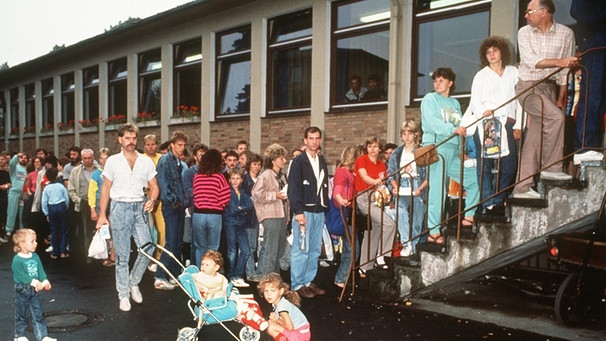 [06.05.1989] Übersiedler aus der DDR stehen in einer langen Schlange im Aufnahmelager in Gießen, um sich registrieren zu lassen. Für viele DDR-Bürger war die Stadt Gießen die erste Station im Westen. | Bild: picture-alliance/dpa